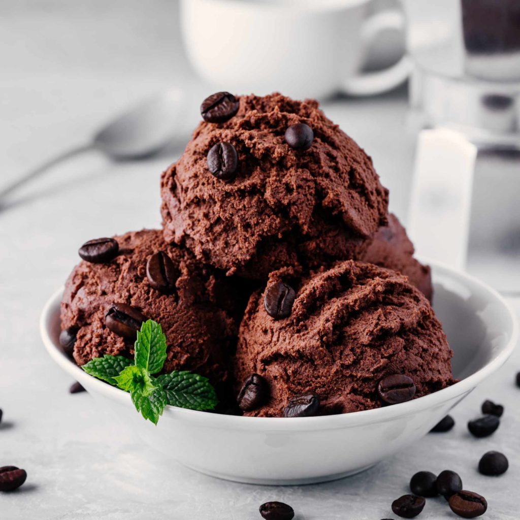 A bowl of chocolate coffee ice cream scoops with mint