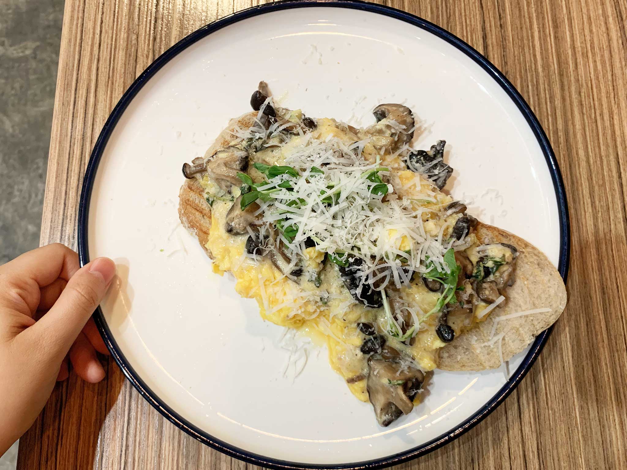 Scrambled eggs on toasted bread topped with sautéed mushrooms
