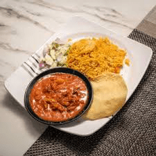 Plate of Indian food featuring a red curry in a black bowl, yellow spiced rice, a piece of puri and a side of kachumber salad