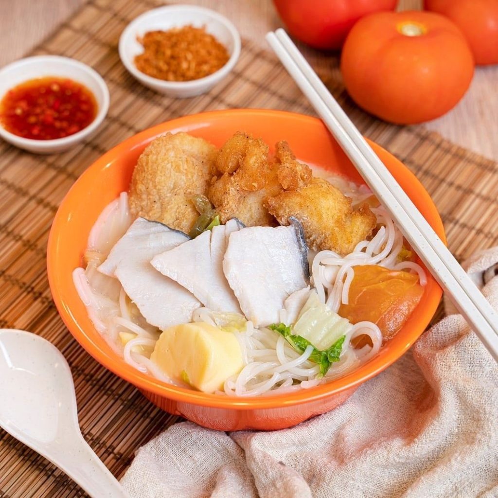 A vibrant orange bowl of mixed fish bee hoon soup from Arcade Fish Soup