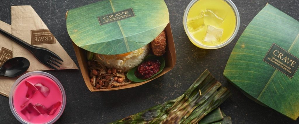 A CRAVE Nasi Lemak takeaway meal spread on a dark surface