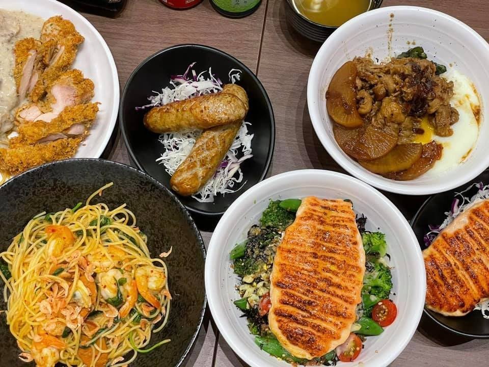 Little Bowl Singapore's diverse menu offerings: grilled salmon grain bowls, shrimp spaghetti, chicken katsu, sausages, and a savory rice bowl, ready for a shared meal