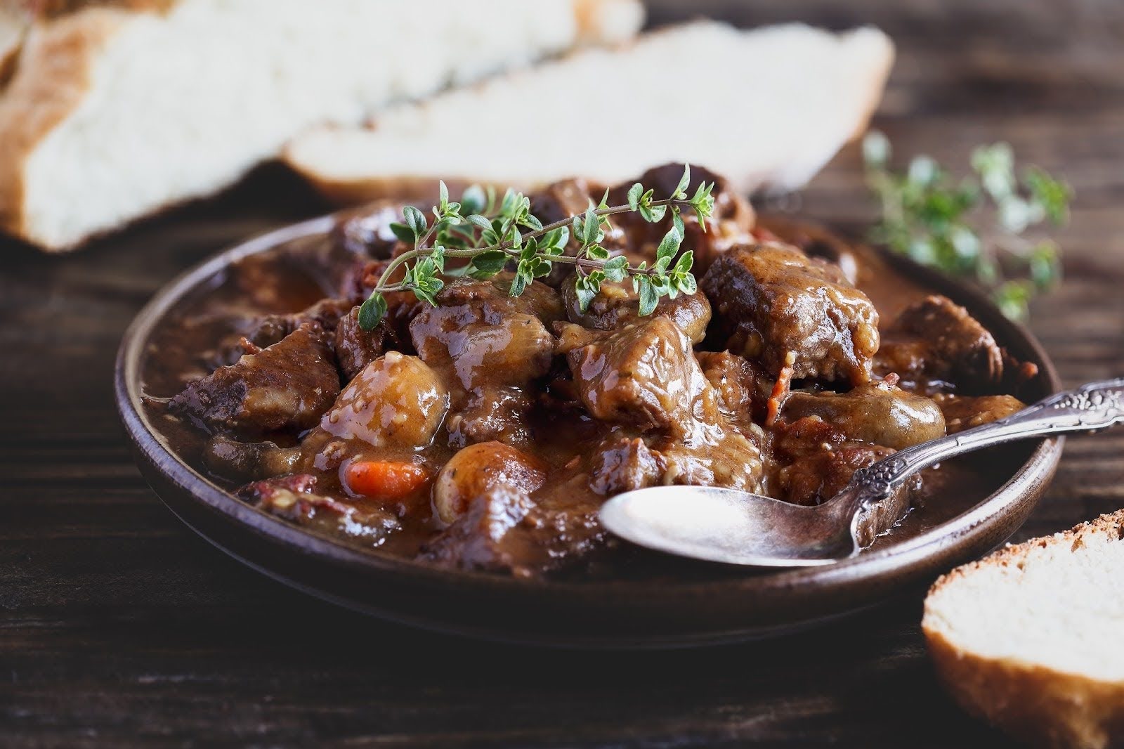 A rustic bowl of rich Beef Bourguignon, garnished with thyme