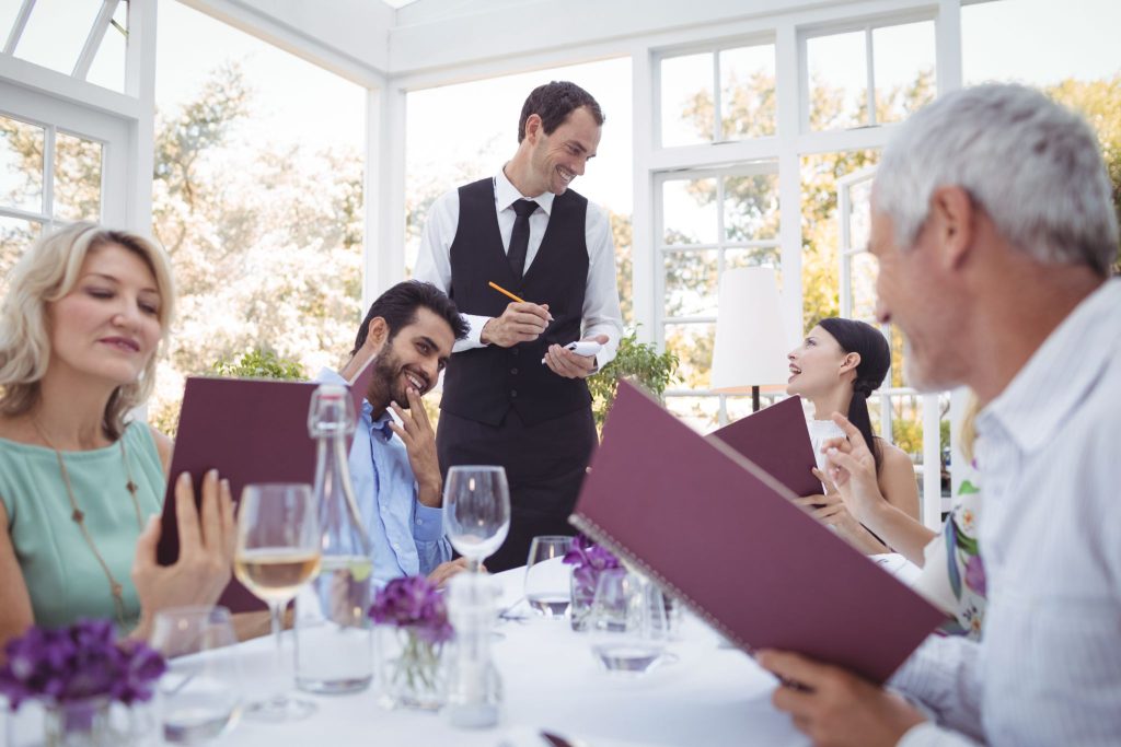 a waiter taking the orders of the table he is serving